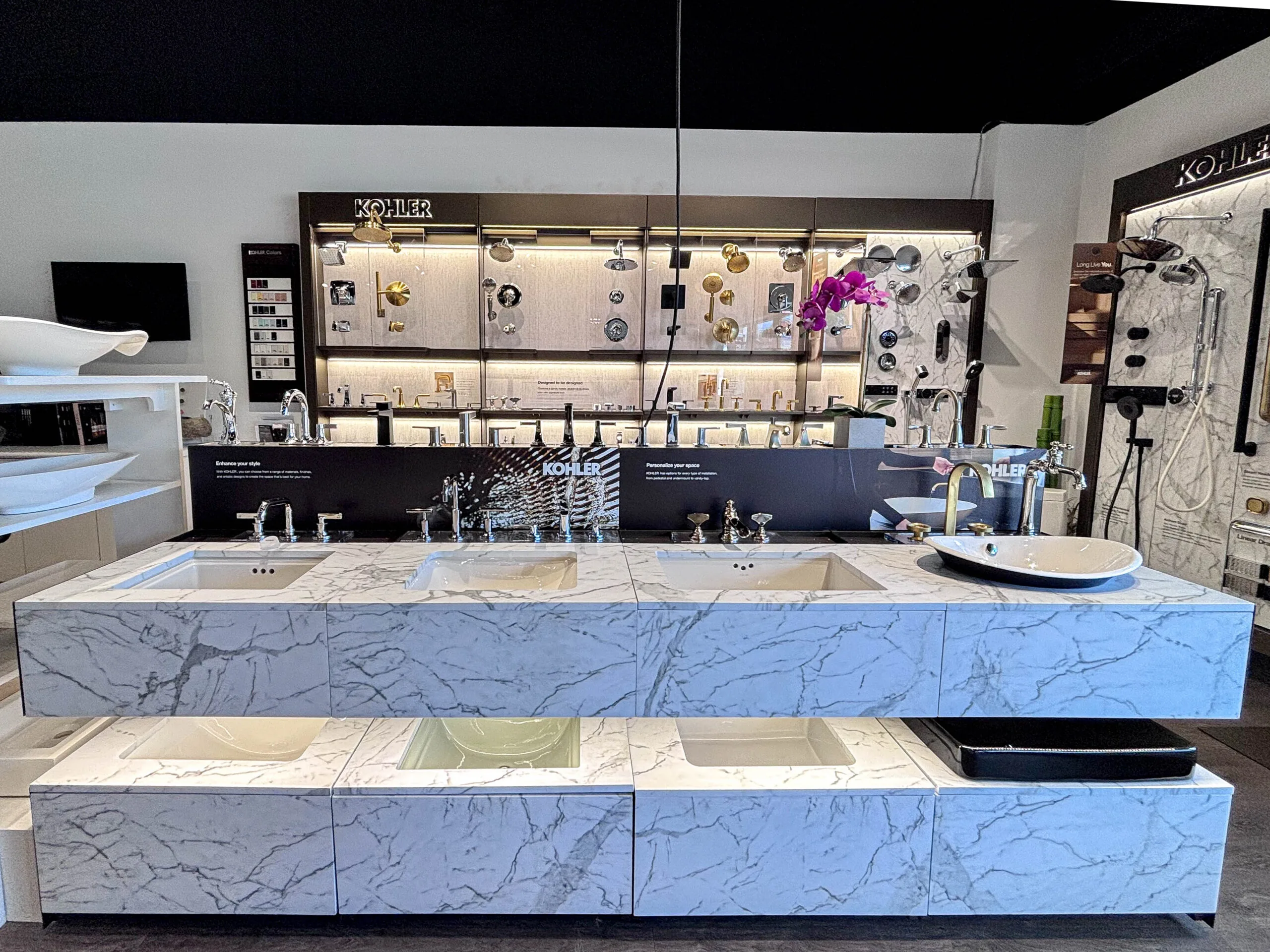 Kohler bathroom sinks and faucets on a marble display counter in the showroom