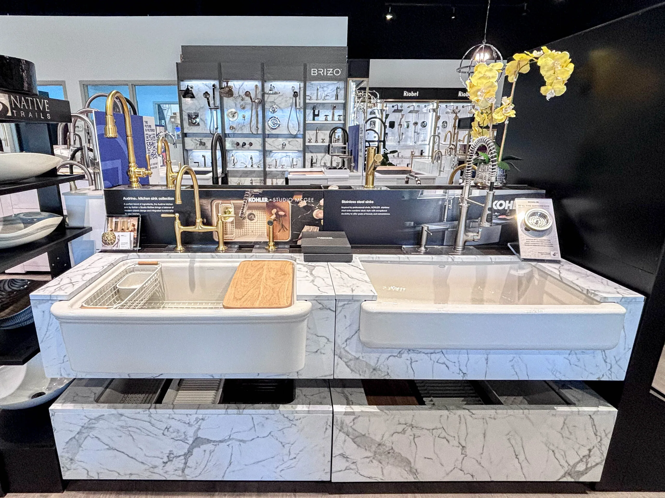 Farmhouse kitchen sinks and faucets on a marble display island in the showroom